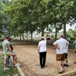 Six personnes de dos, sur le terrain de pétanque s'affrontent