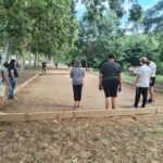 Six personnes de dos s'affrontent sur le terrain de pétanque