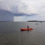 Un résident sur l'eau dans un kayak rouge pagaie