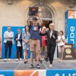 Un jeune homme fier soulève son trophée devant l'ensemble du public et des partenaires