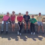 Le groupe de jeunes assis sur un muret et en arrière plan la plage et la mer