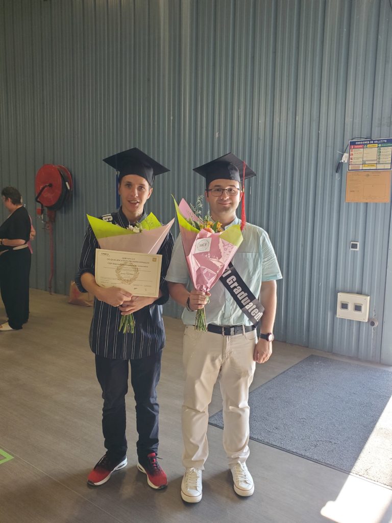 David et Jimmy posent avec leurs certificats et un bouquet de fleurs chacun