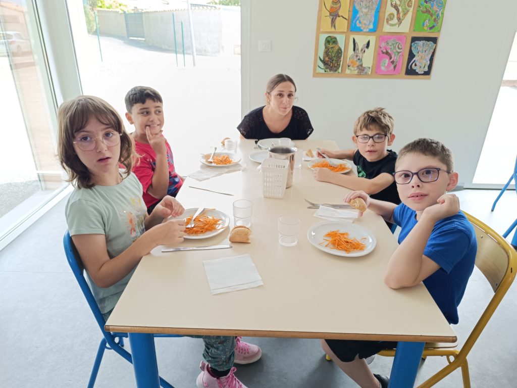 4 enfants à table avec leur accompagnatrice