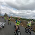 Pendant la course, les jeunes en chasuble jaune fluorescent, sur la route à vélo