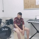 Une jeune fille au chant et un jeune homme assis près du clavier