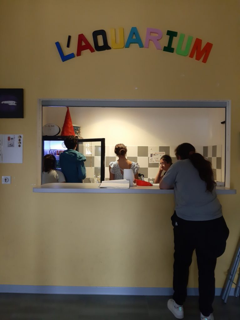 Photo de l'Aquarium dans le gymnase de l'IME. Des jeunes de chaque côté du comptoir