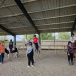 Dans le manège, les résidents à cheval et les accompagnatrices à terre