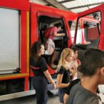 Des jeunes avec une femme pompier près du camion rouge