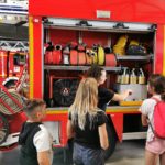 Les jeunes devant le camion de pompier. Un femme pompier leur donne des explications sur le fonctionnement du matériel