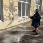 Un jeune nettoie la façade des classes avant rénovation
