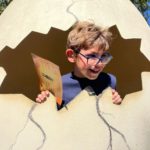 Un jeune garçon pose dans un faux œuf géant