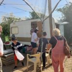 Jeunes et adultes près du verger, en arrière plan une caravane