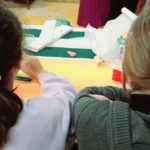 Deux jeunes filles de dos s'affairent à la table de couture
