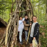 3 jeunes dans une hutte construite avec des branches