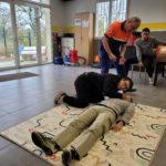 Deux jeunes effectuent un exercice avec le formateur. Les autres les regardent