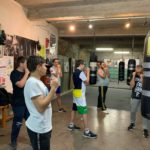 Dans la salle de sport, cinq jeunes apprennent à positionner les poings avec leur professeur