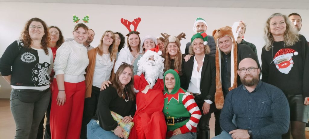 Photo de groupe des professionnels en tenues de Noël (déguisements de lutin, de Père Noël, de rennes,...)