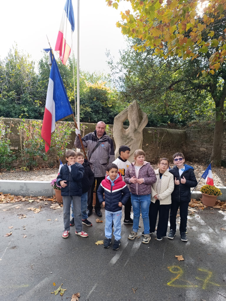 Les élèves près du porte drapeau devant le monument aux morts