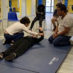 Deux jeunes en plein exercice avec le formateur. Deux autres jeunes regardent