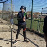 Un jeune homme dans la "cage" avec son casque et sa batte
