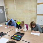 Trois jeunes autour de la table dessinent