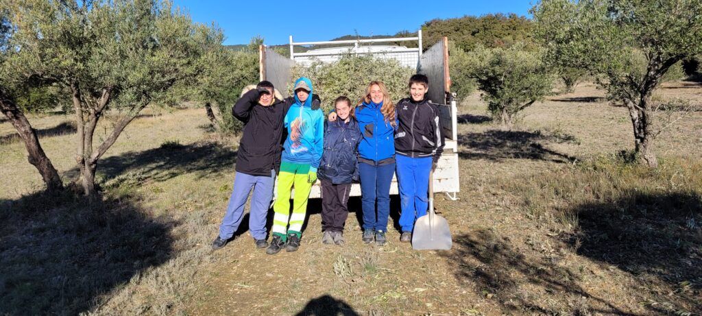 Les jeunes et leur encadrante devant le camion benne dans l'oliveraie