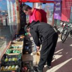 Deux jeunes à l'entrée d'un supermarché rangent les produits récoltés