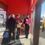 Deux jeunes à l'entrée d'un supermarché collectent des produits auprès des clients