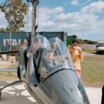 Deux jeunes dans le cockpit d'un hélicoptère avec un autre jeune debout à leurs côtés