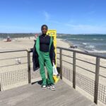 Une jeune sur un ponton devant le sable et la mer