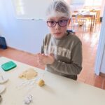 Un petit garçon avec une charlotte sur la tête prépare un sablé