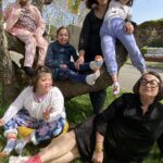 4 enfants avec 2 accompagnatrices assises dans l'herbe avec leurs chaussettes dépareillées