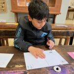 Un jeune garçon, en classe, écrit à la plume