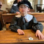 Deux jeunes, en classe, à leur bureau, avec les tenues d'écoliers d'antan