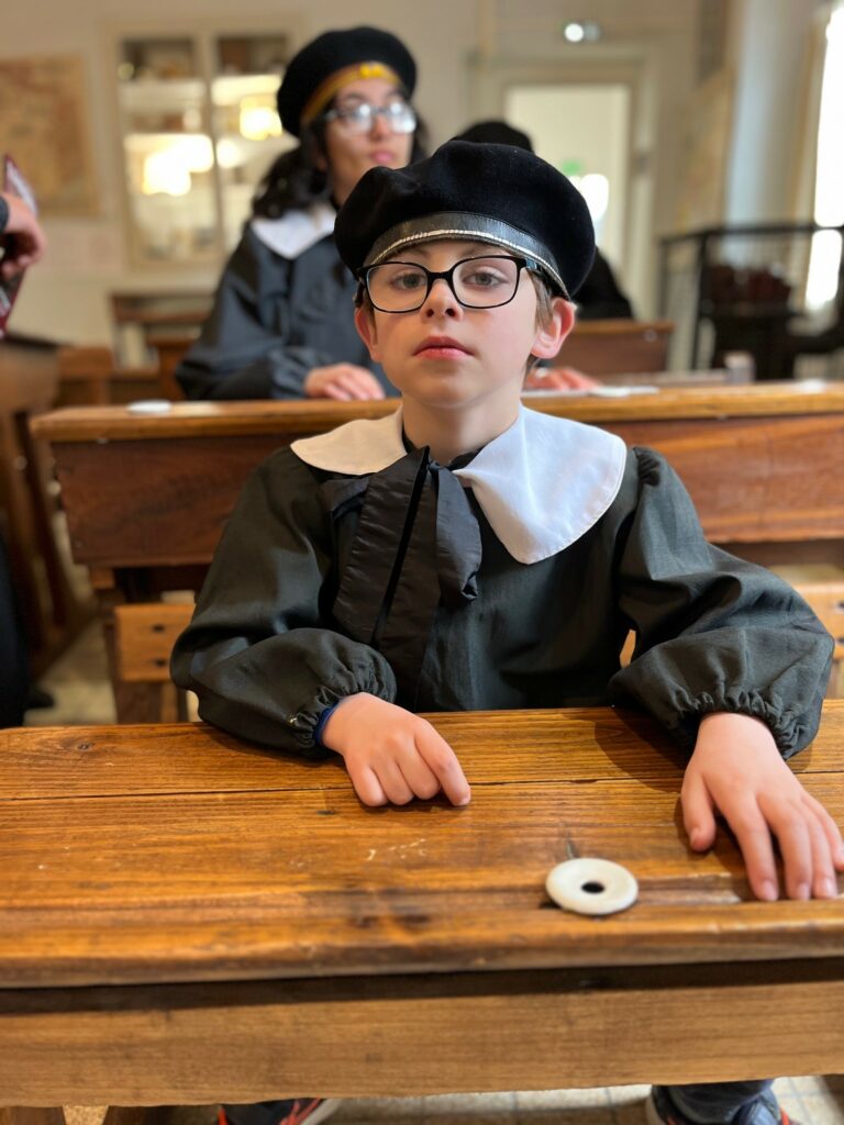 Deux jeunes, en classe, à leur bureau, avec les tenues d'écoliers d'antan