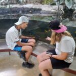 Deux jeunes assis sur un banc regardent les reptiles dans le grand vivarium