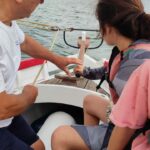 Une jeune fille tient la barre, à l'avant du voilier, avec Monsieur Pujol