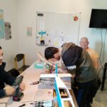 2 jeunes et 1 parrain autour d'une table construisent un avion