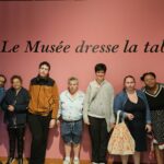Le groupe pose devant le mur "Le Musée dresse la table"