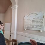 Deux élèves, pendant la préparation de la commémoration, se rendent à la Mairie, et lisent une plaque sur laquelle appariassent tous les noms des personnes disparues durant la guerre : "Les morts glorieux"