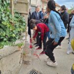 Les jeunes déposent des roses au pied du mur sur lequel la plaque est posée
