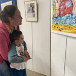 Un petit garçon devant une toile dans les bras d'Elena
