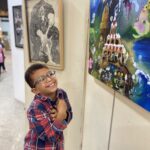 Un petit garçon souriant devant une toile
