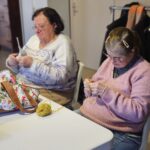 Magali tricote à côté d'une autre adhérente de l'association.