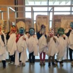 Dans les locaux de Narbo Via, huit jeunes portant des toges et les masques qu'ils ont confectionné.