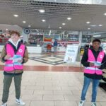 Deux jeunes distribuent des prospectus à l'entrée du supermarché