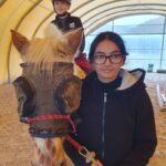 Un jeune sur un poney tenu par la bride par une autre personne