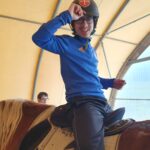un jeune accompagné en selle. en arrière plan un autre jeune