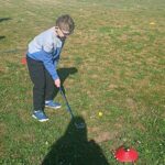 Un garçon joue au golf sur une pelouse