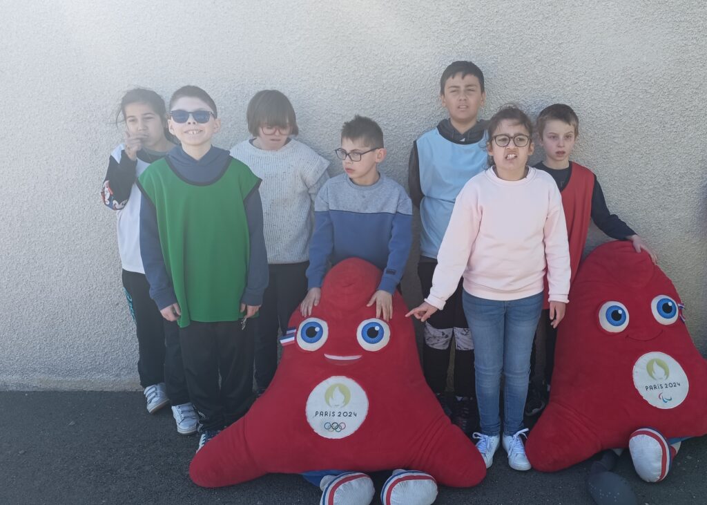 7 jeunes posent avec deux phryges, mascottes des JO d'été de Paris